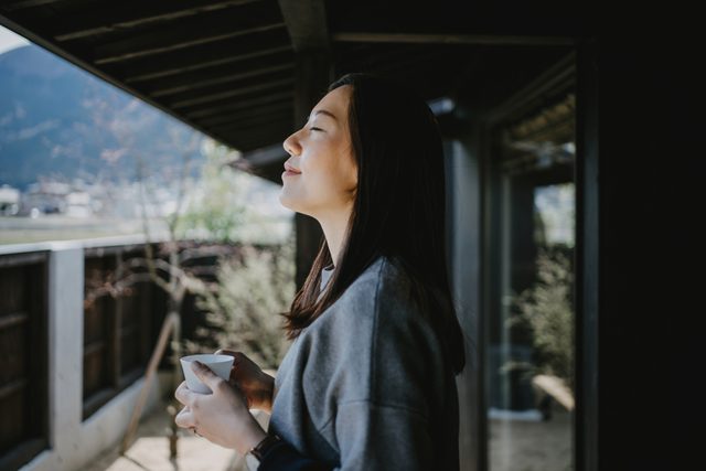 young woman taking a deep breath outside