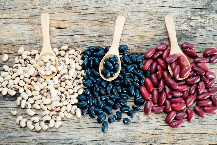 Wooden spoons full of pinto, black, and kidney beans