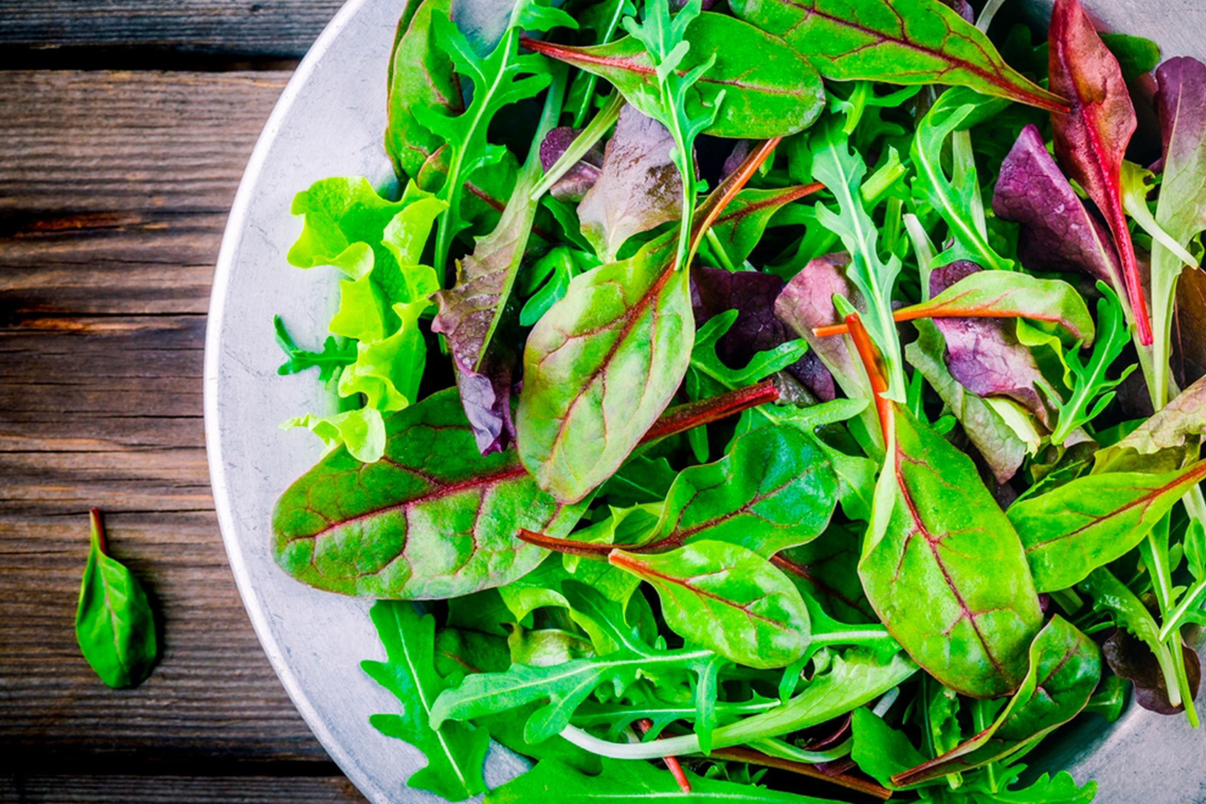 Leafy greens in a white bowl on a wood background