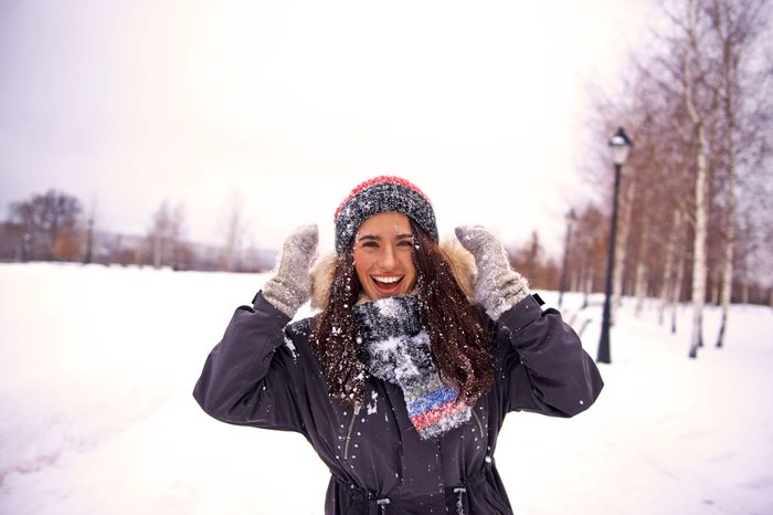 Woman in a scarf and coat outside in the snow.