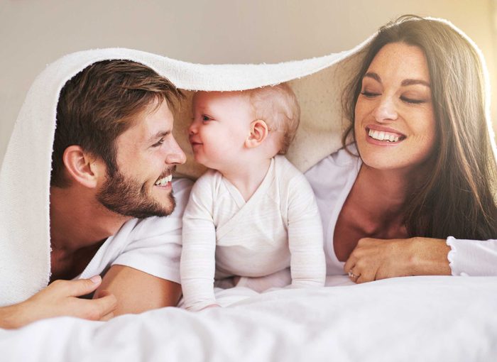 Happy couple in bed with baby between them