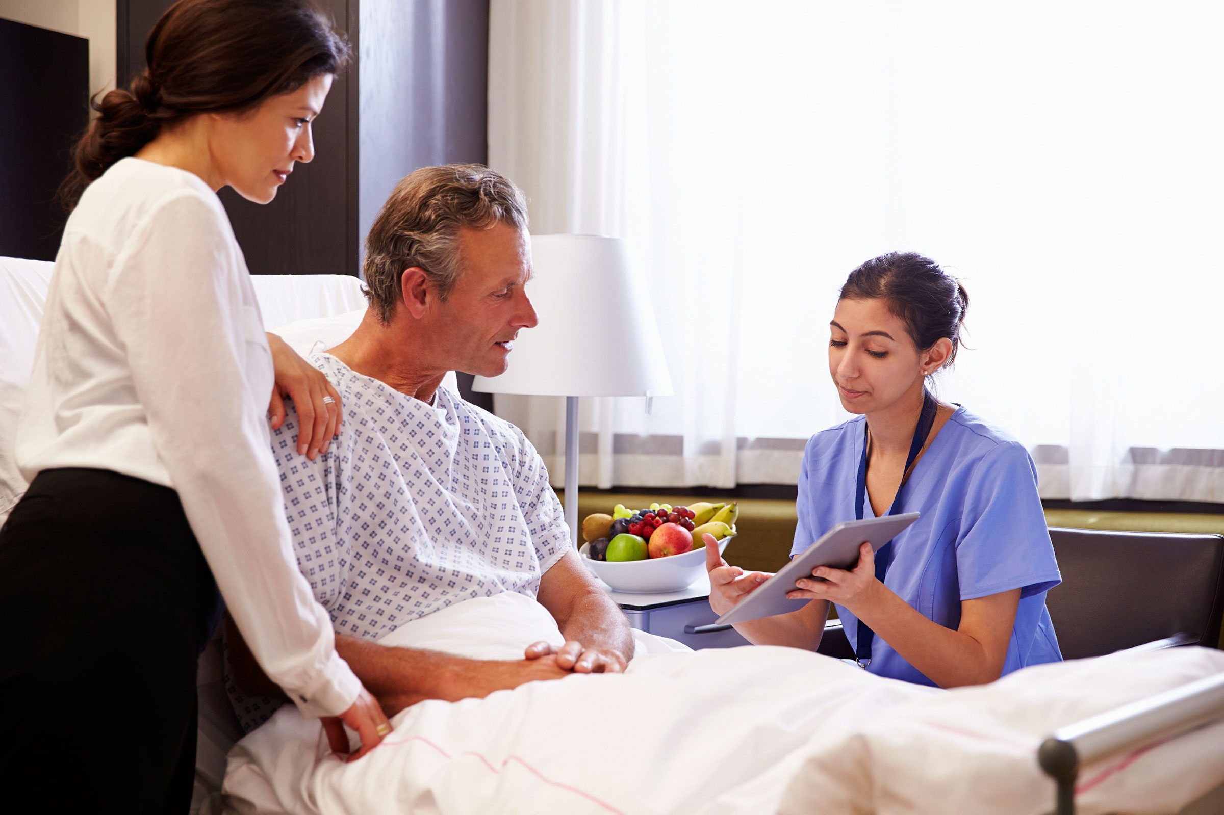 man in hospital bed with family listening to female doctor