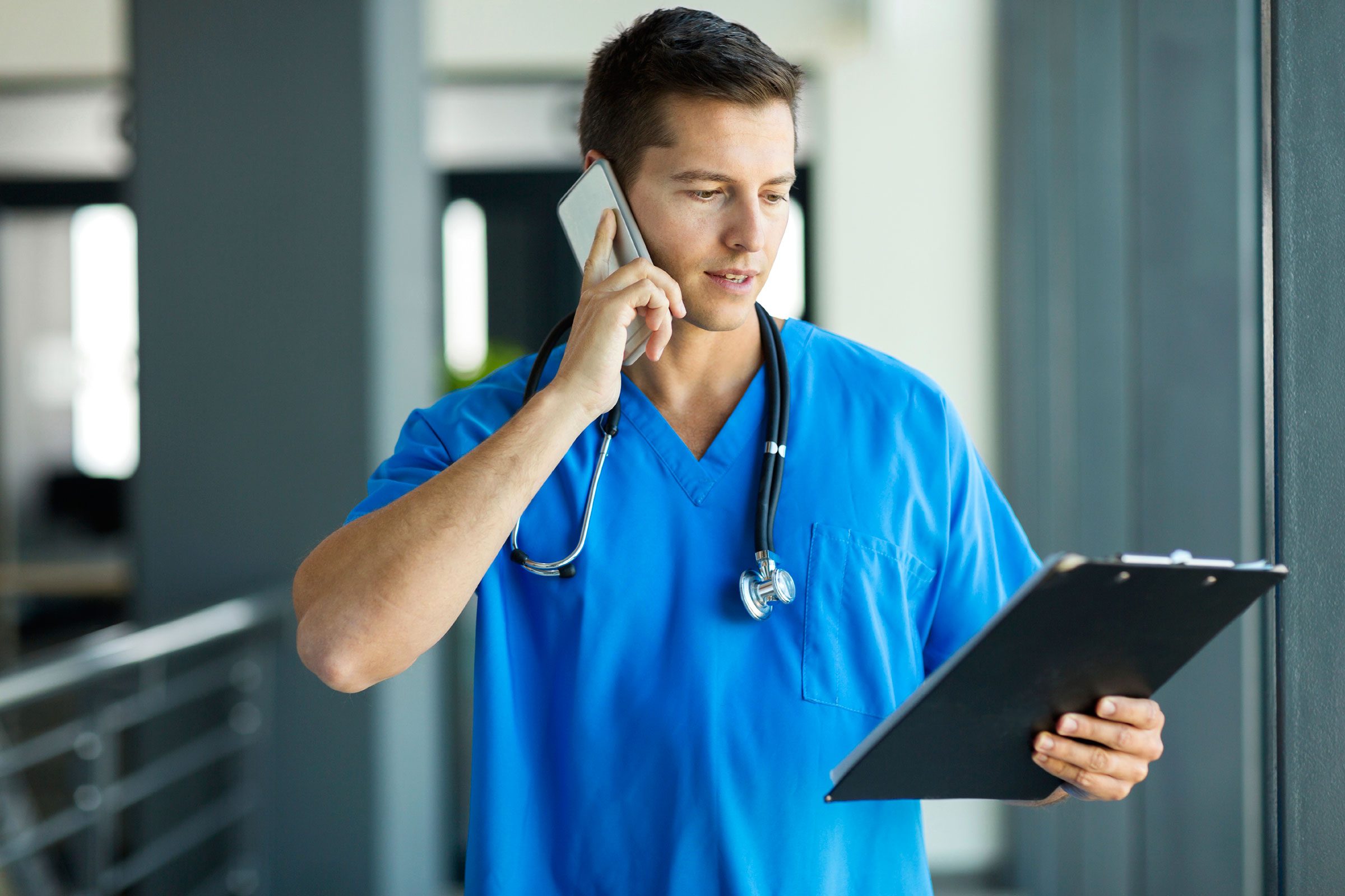 Young doctor on a phone and looking at a clipboard