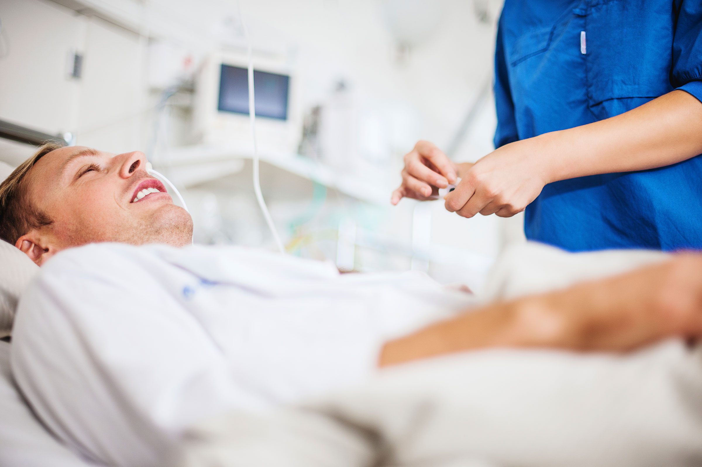 man in a hospital bed being attended to