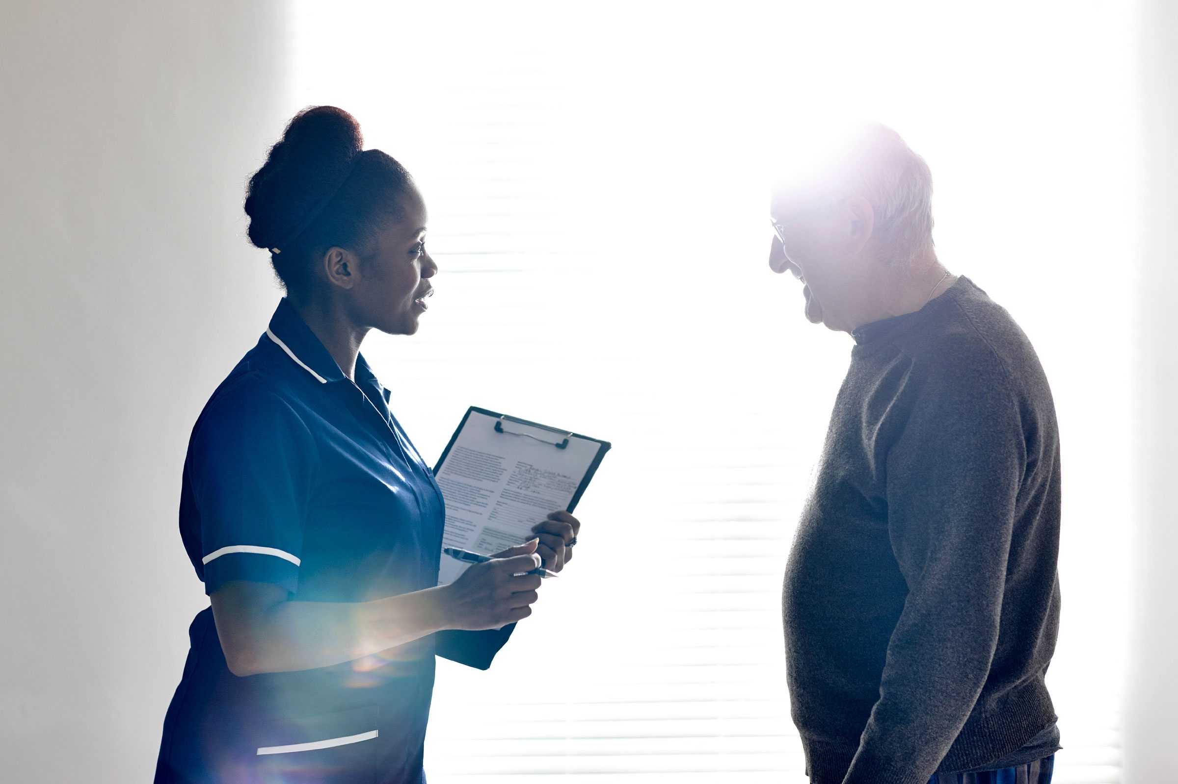 black nurse discussing care with elderly man