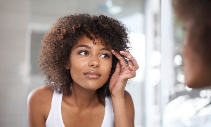 woman examining her face in mirror