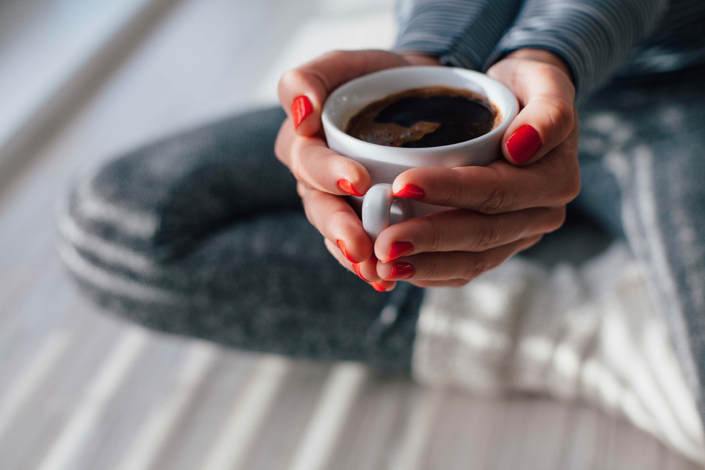 woman's hands cupping a mug of coffee