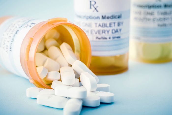 prescription pill bottles, one open on its side spilling tablets