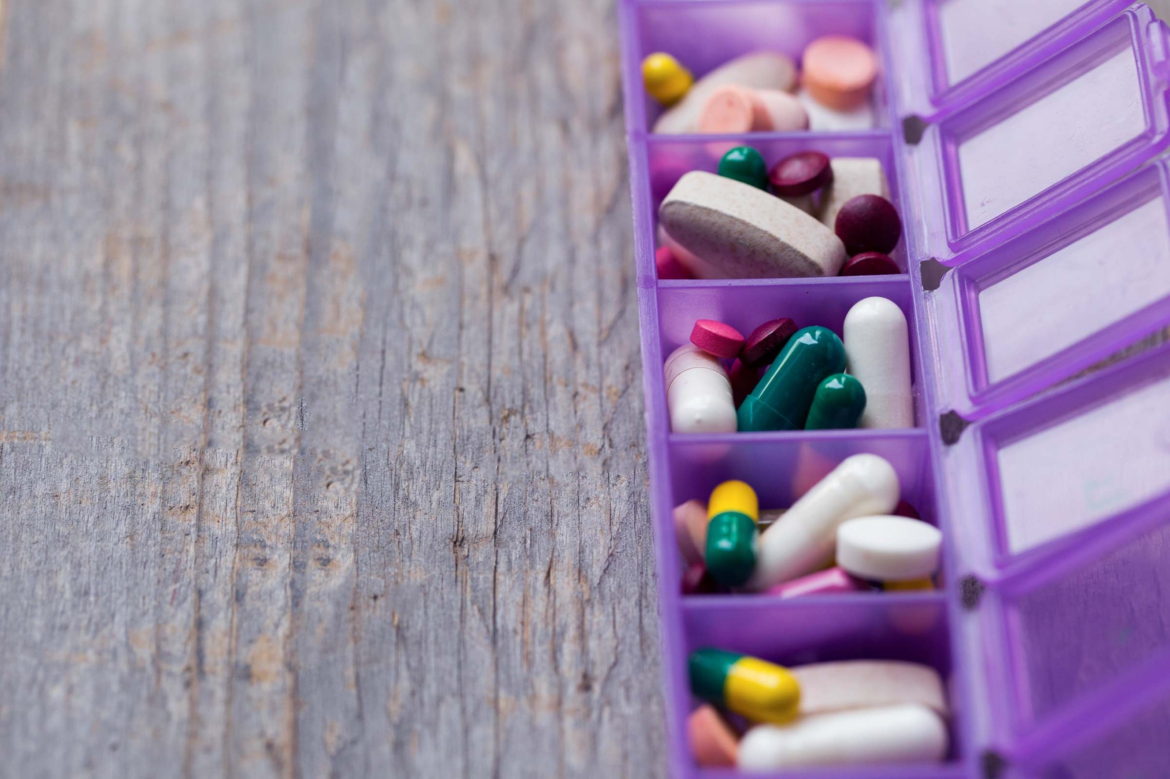 purple pill case filled with pills of different shapes and colors