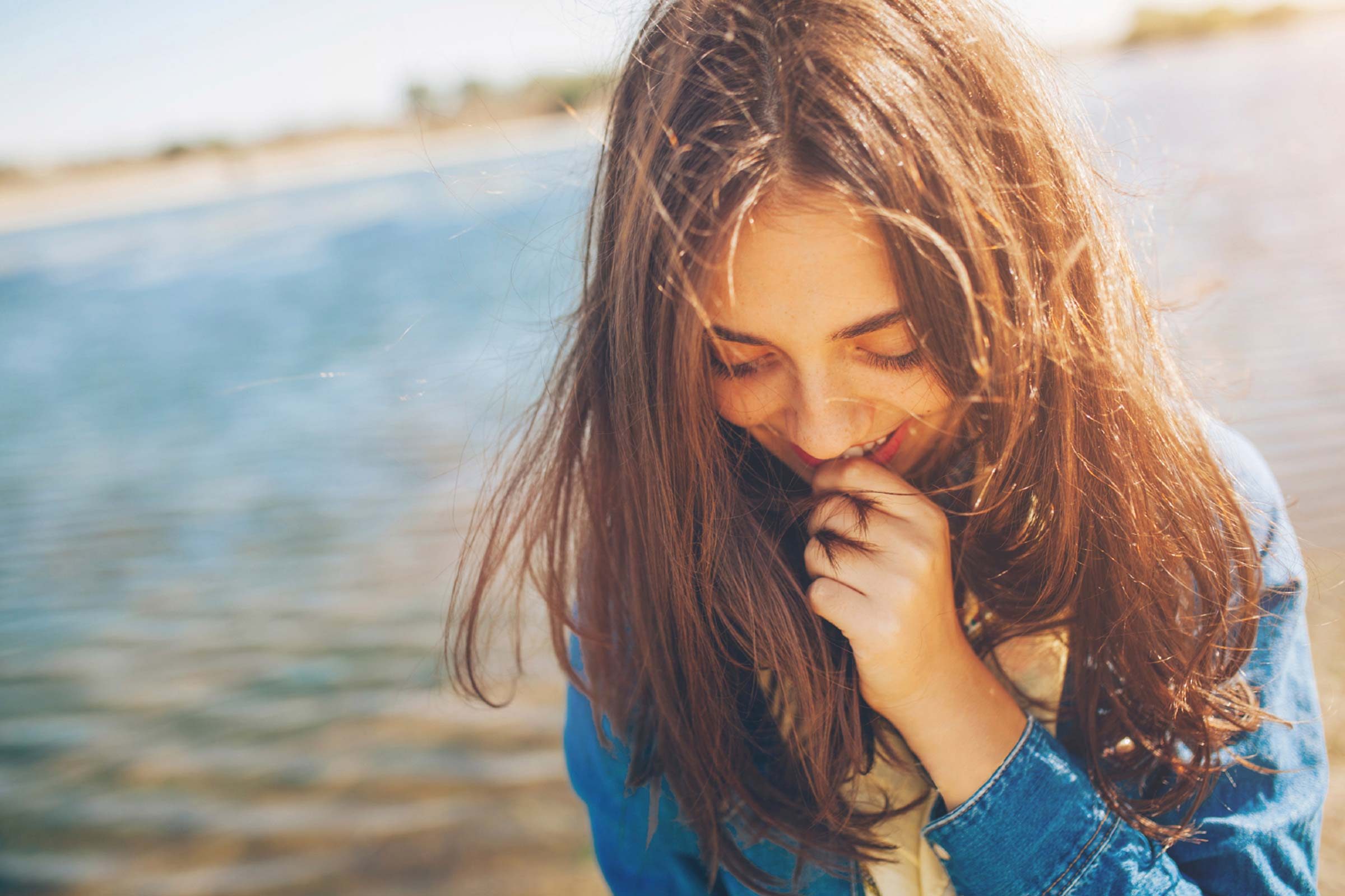 woman in front of lake, smiling and looking down