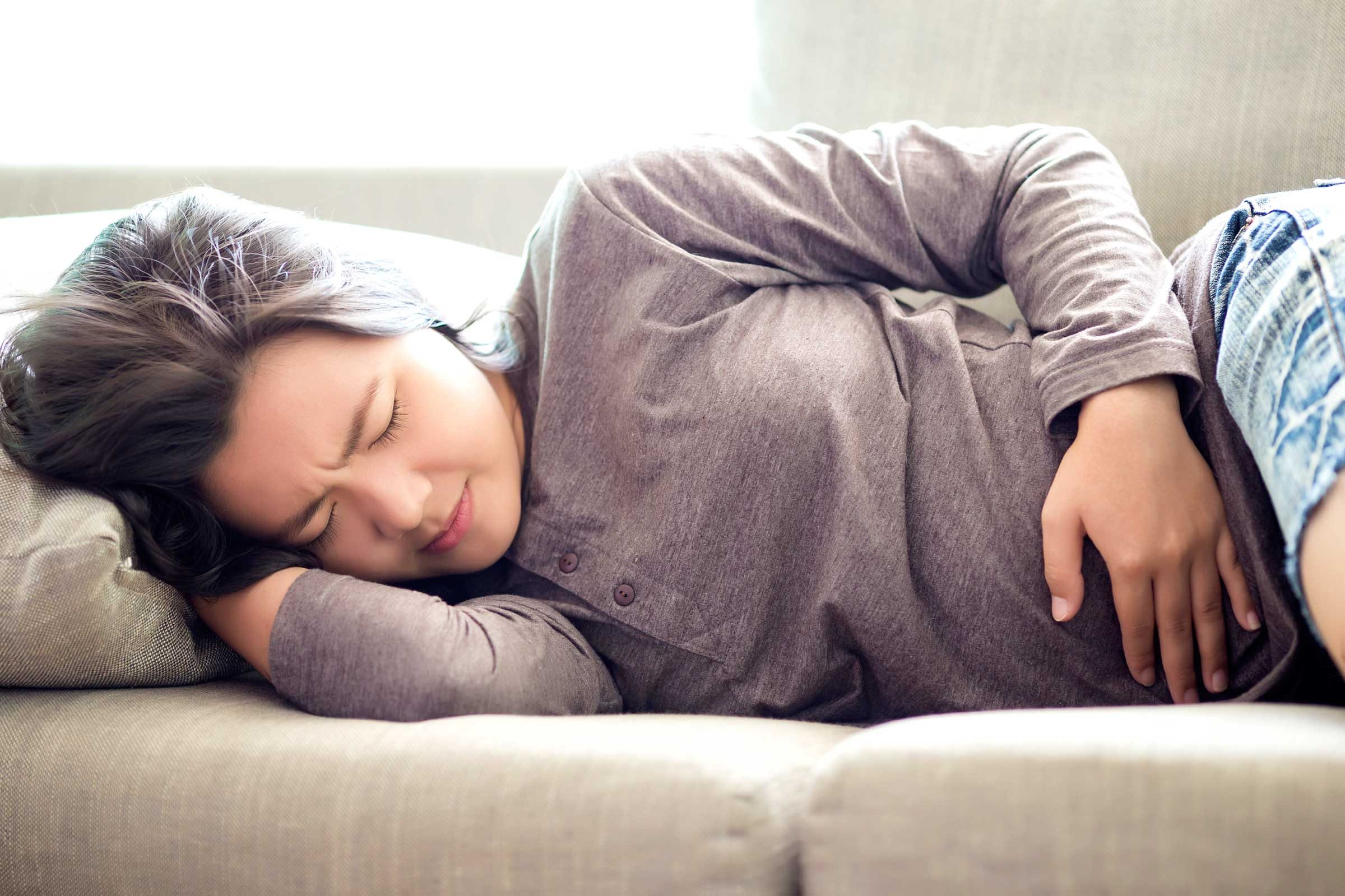 Woman on her side holding her stomach in pain