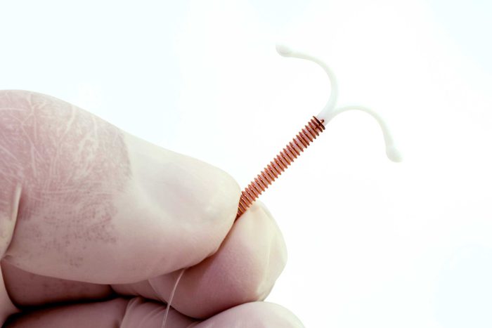 gloved hand holding IUD