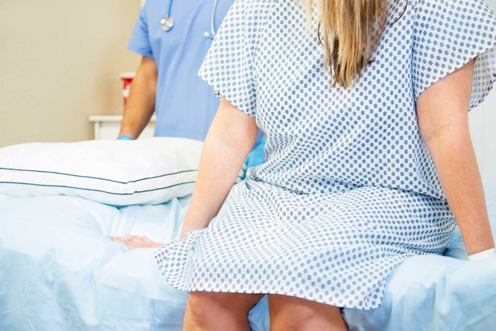 woman sitting on exam table in gown