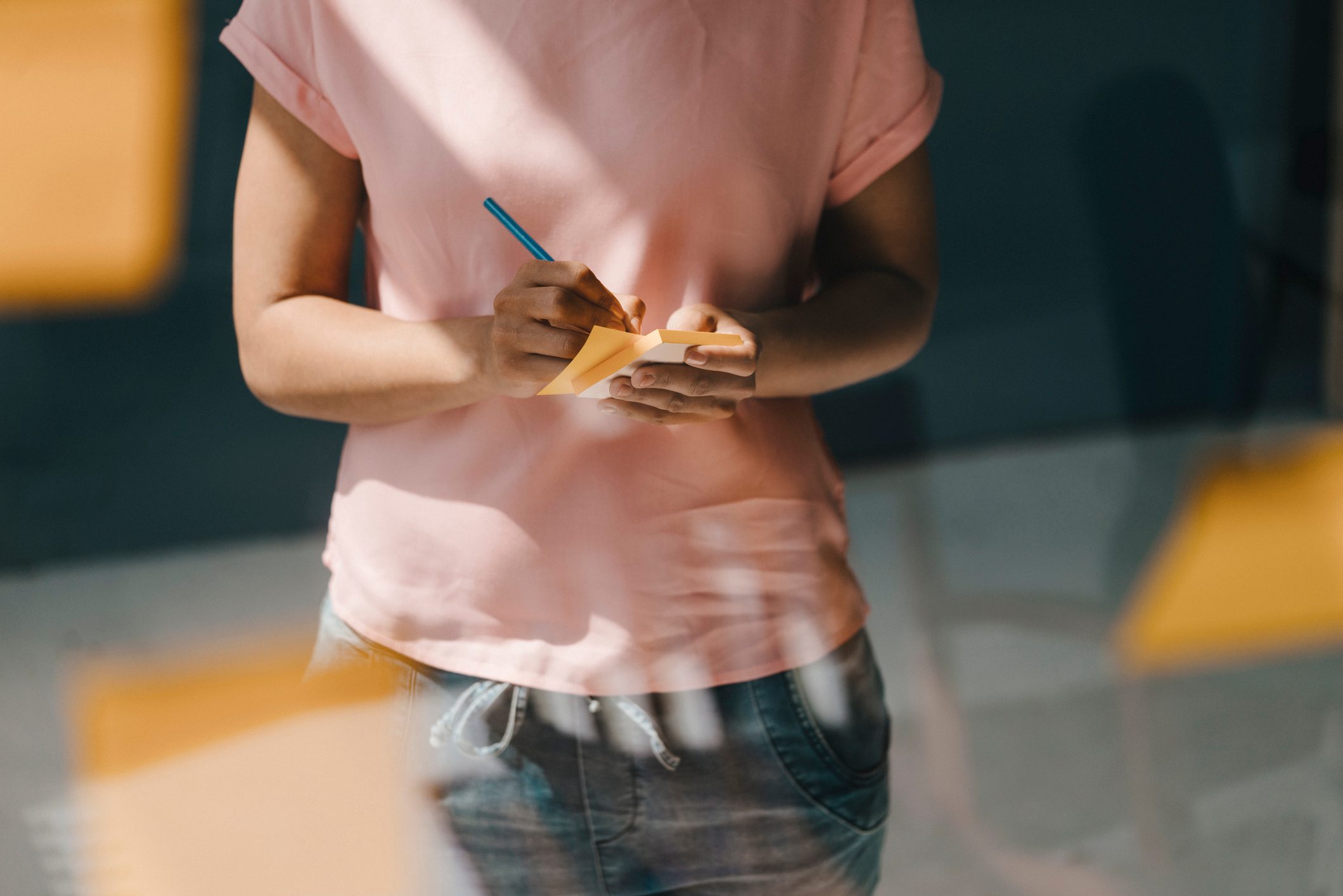 cropped shot of woman writing on sticky note