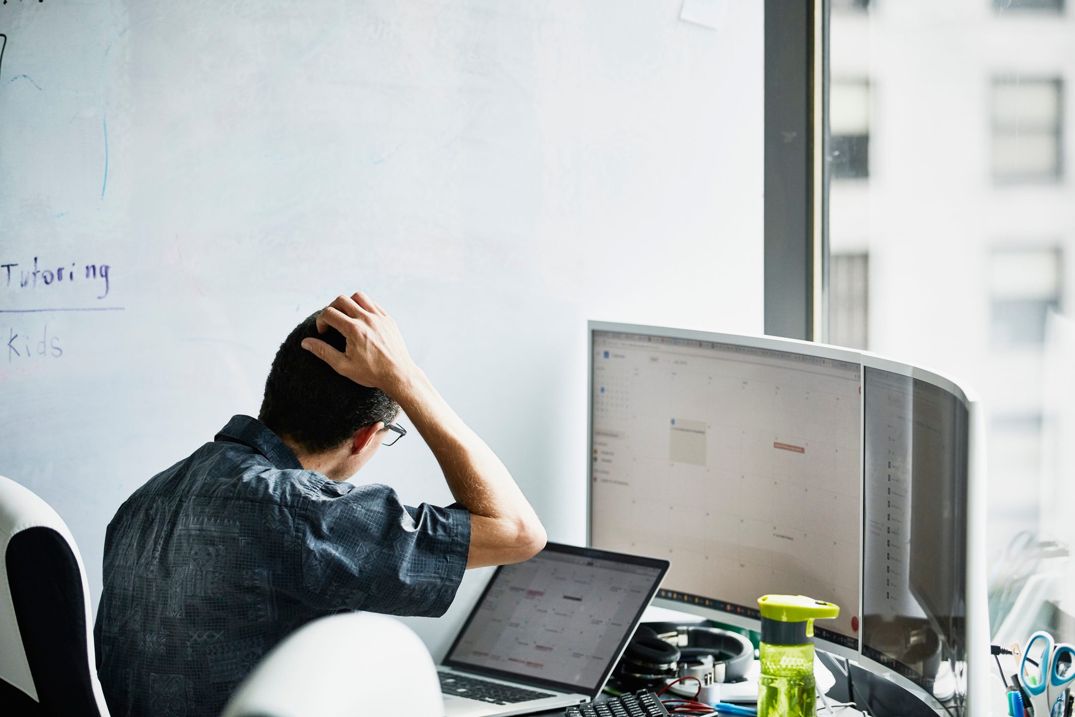 man working and scratching his head while looking at computer
