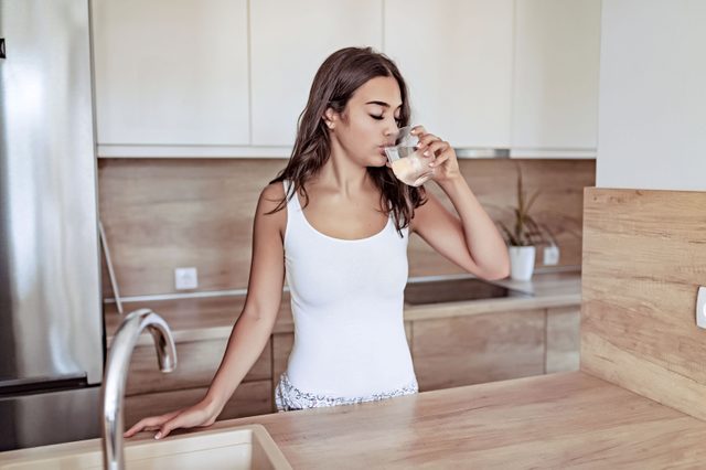 woman drinking water in kitchen