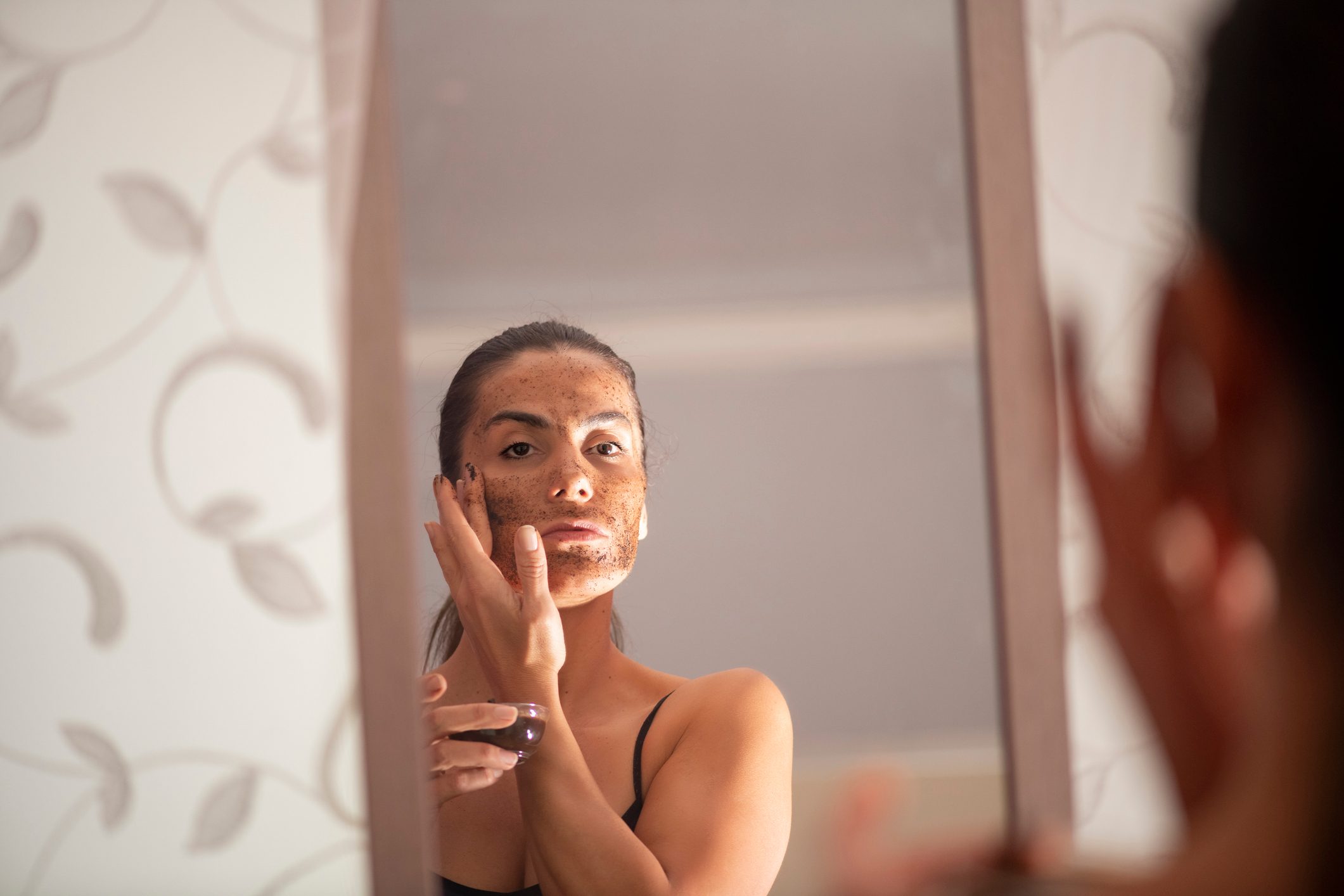 woman applying coffee face mask on face