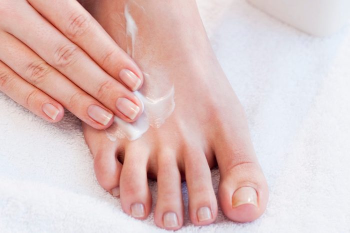 close up of woman applying lotion to foot
