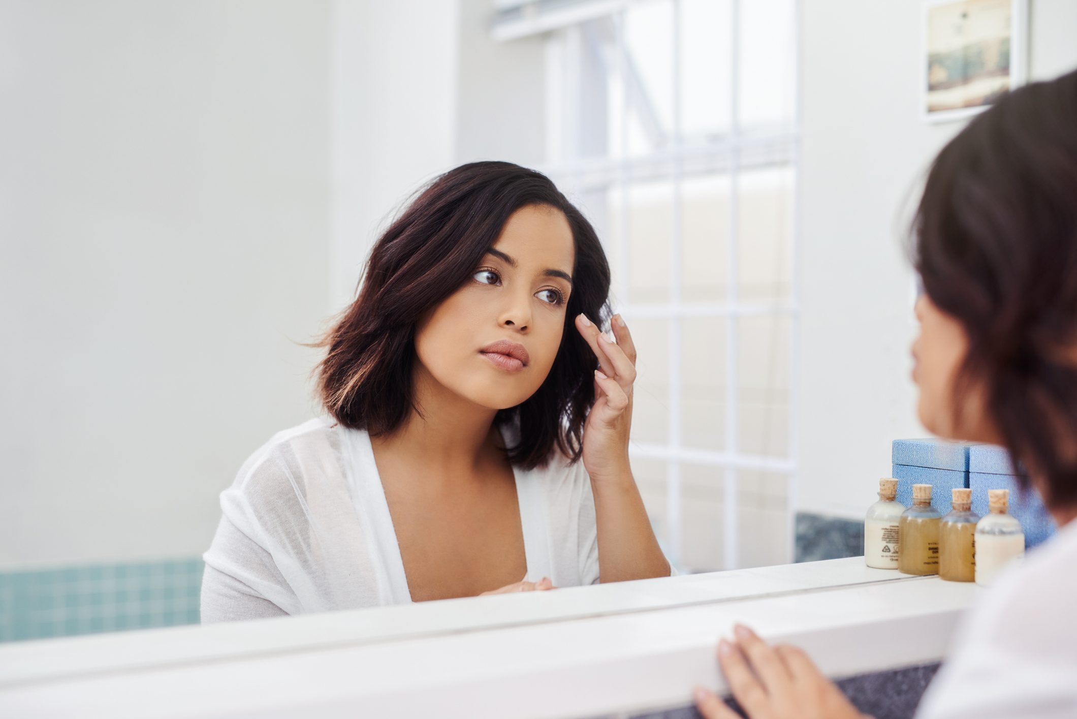 woman looking at face in mirror