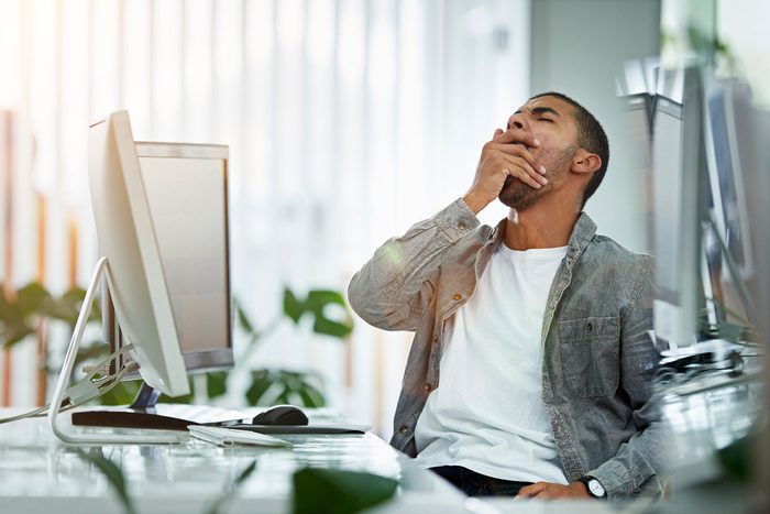 Man yawning while sitting at a desk
