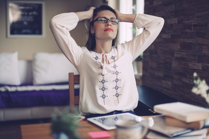 stressed woman at office desk, hands on head