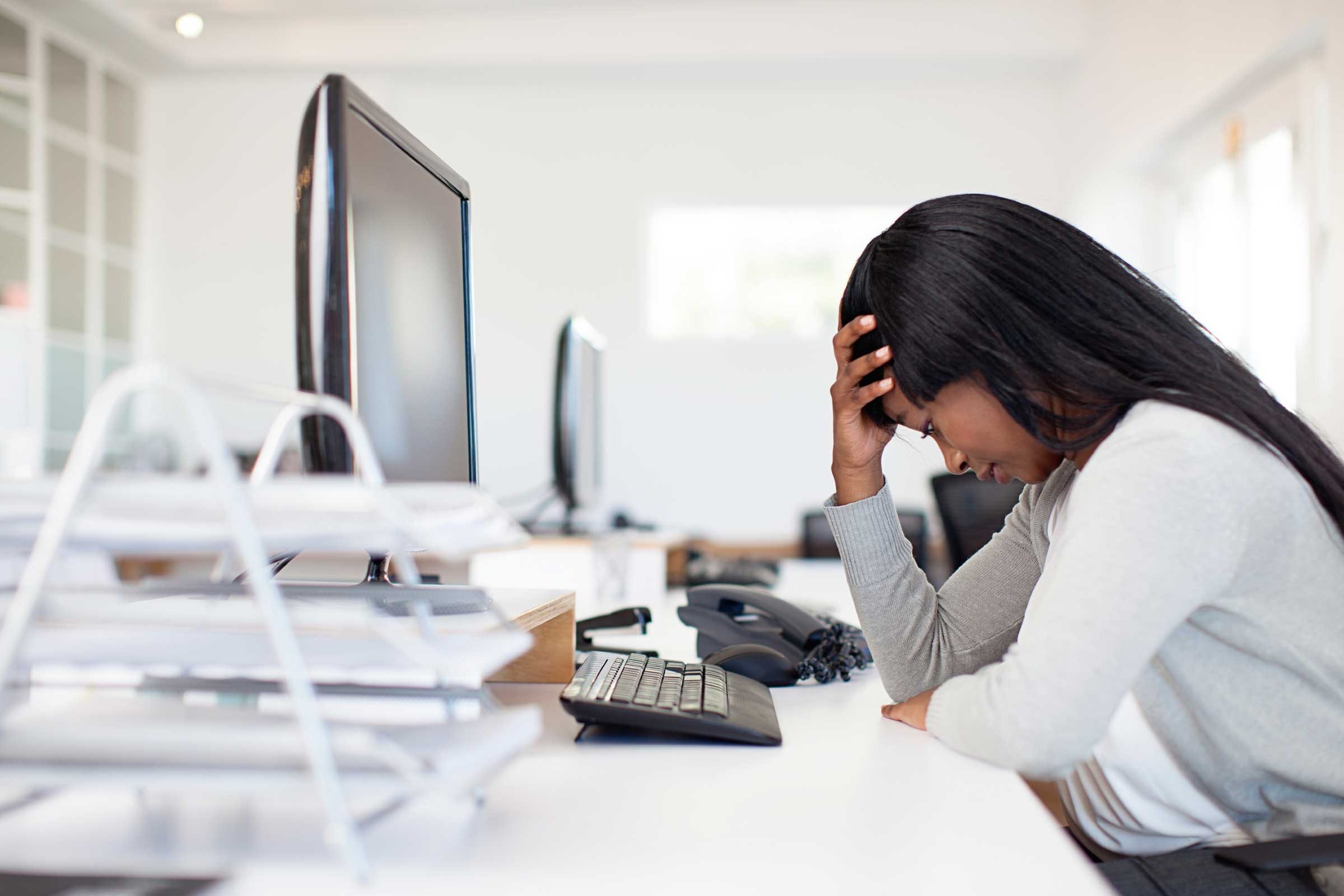 woman sitting at desk with head in hand