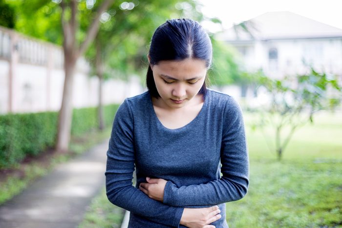 woman with head down, hands clutching stomach