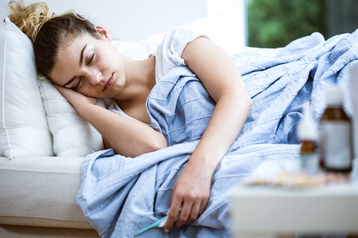 woman on her side in bed, looking ill