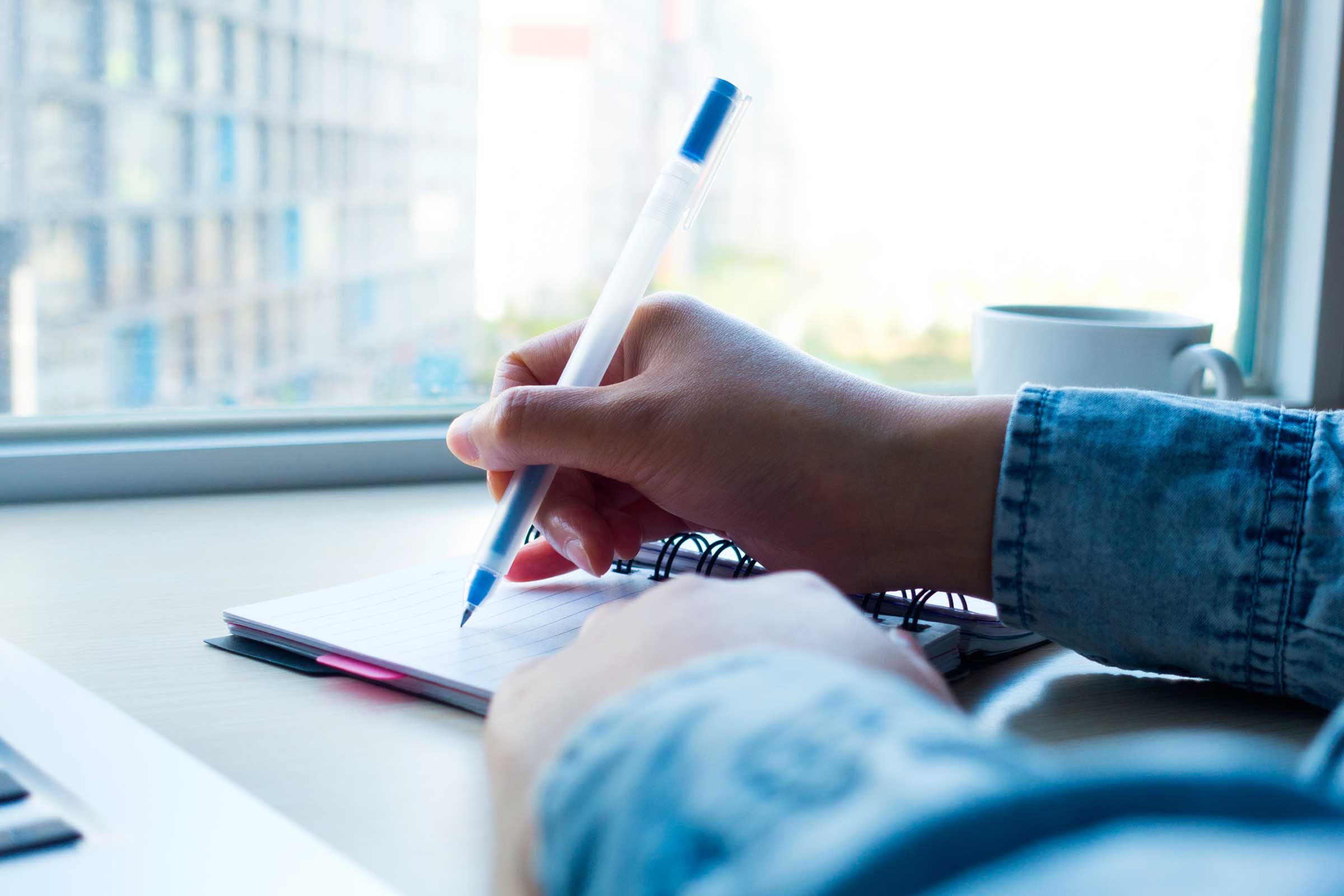 person writing on pad at desk