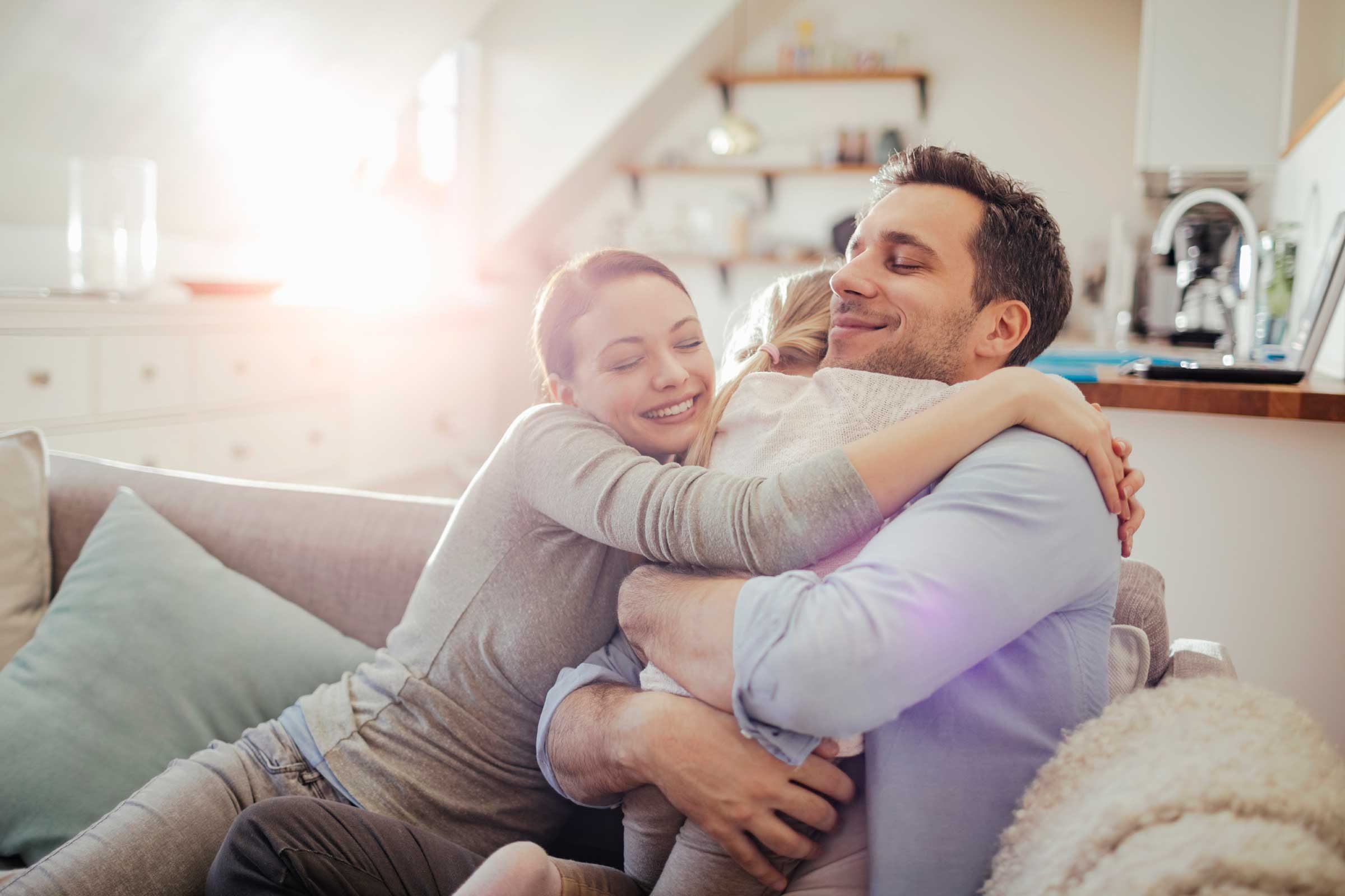 happy family, parents and child, hugging on couch