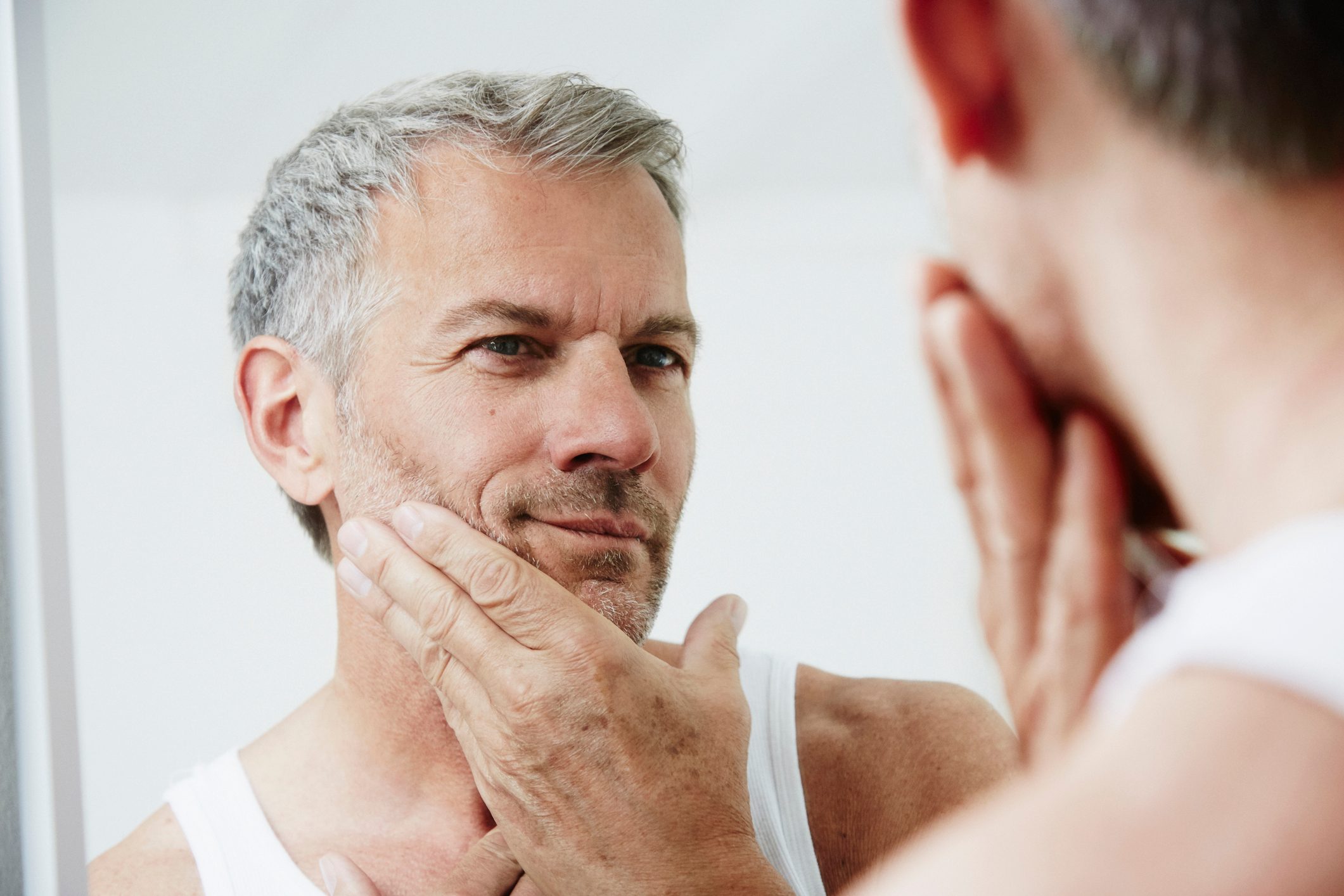 man looking at face in mirror