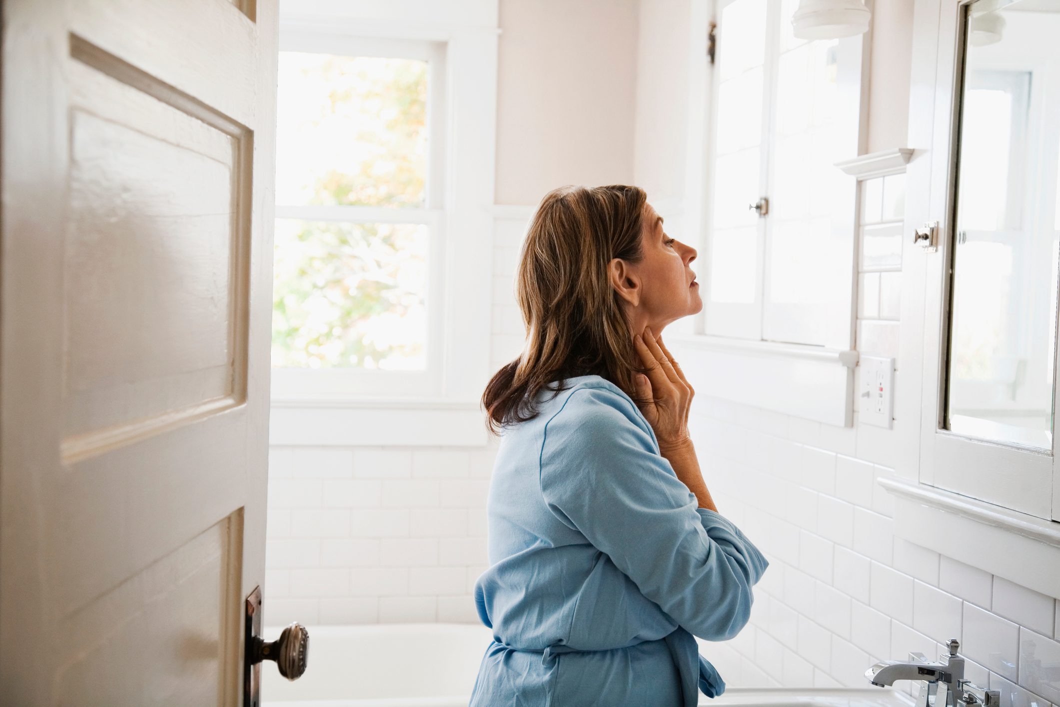 mature woman looking in the mirror in bathroom