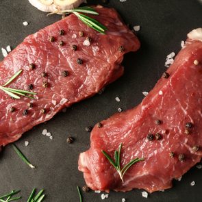 Fresh raw meat with spices on plate, closeup