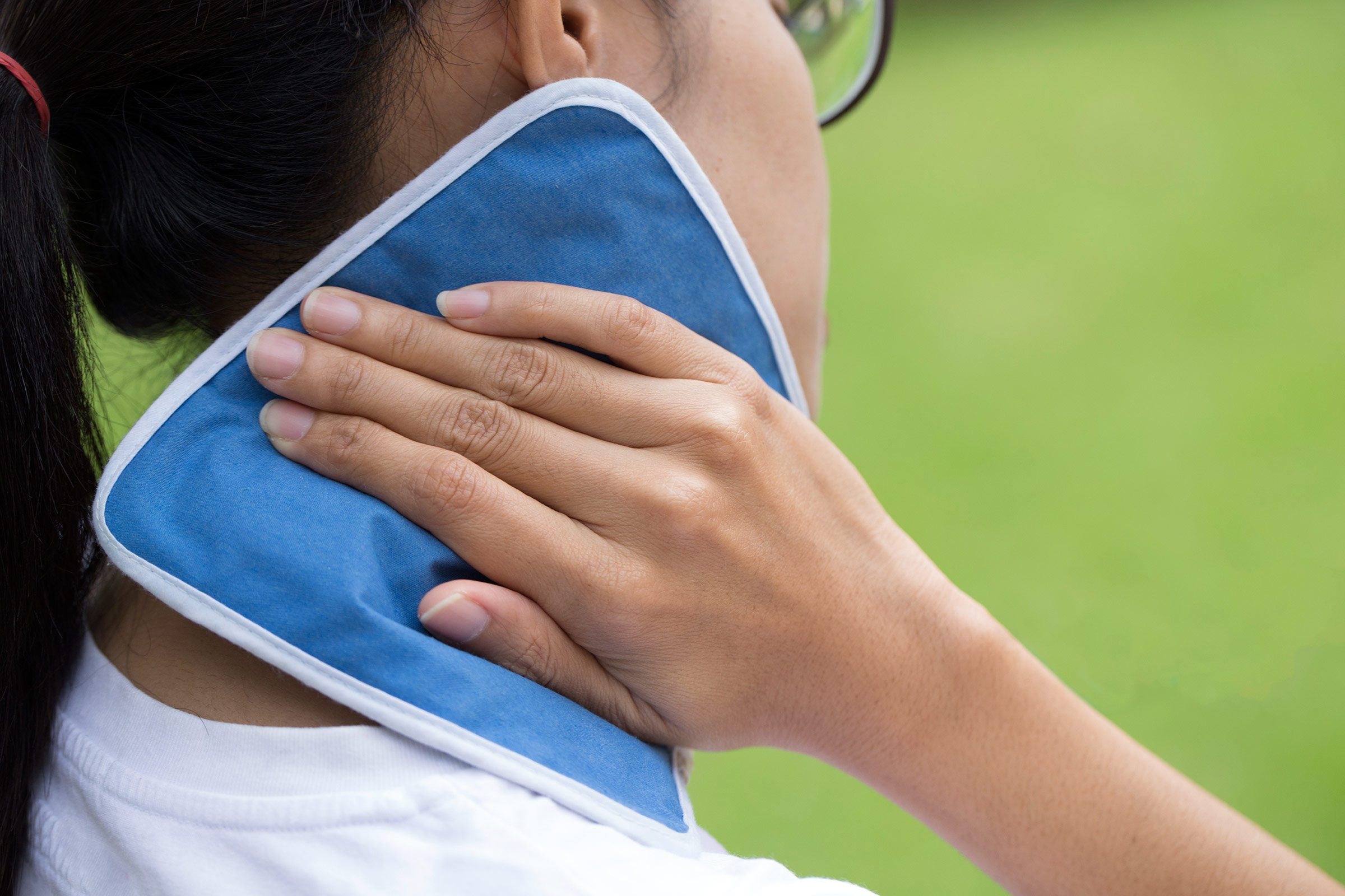 woman holding compress to her neck