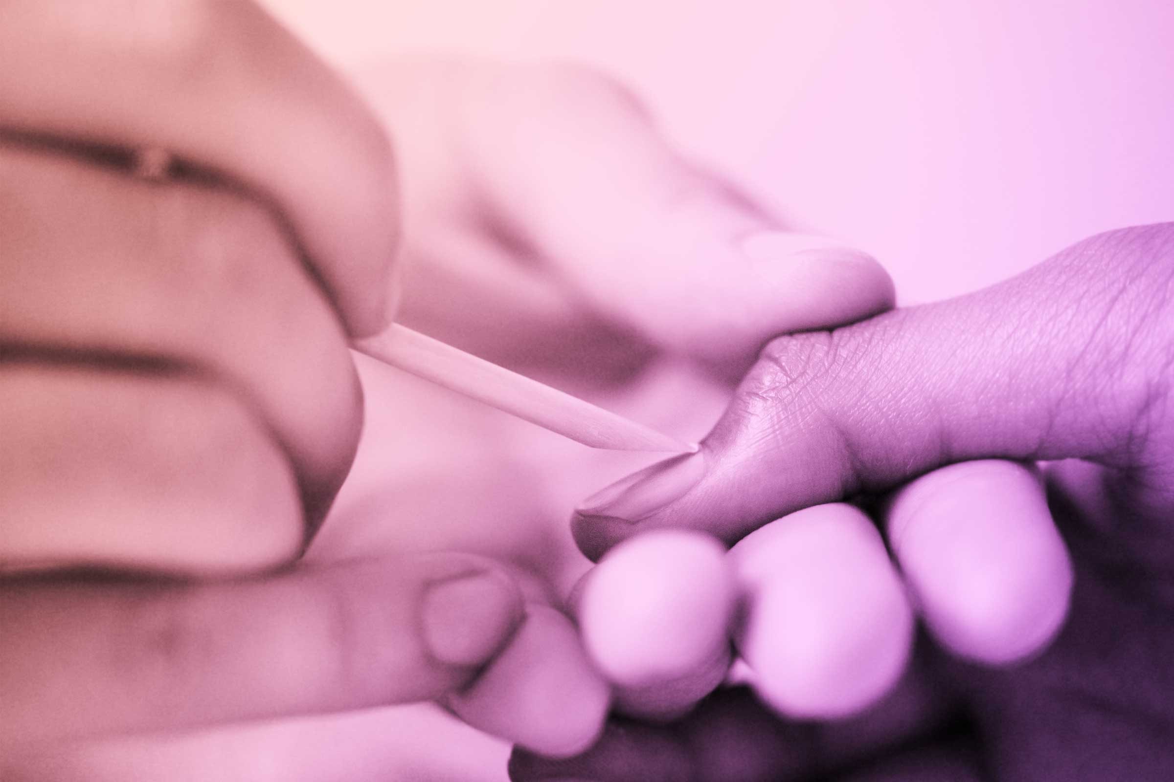 person gently pushing cuticles back on fingernails with tool