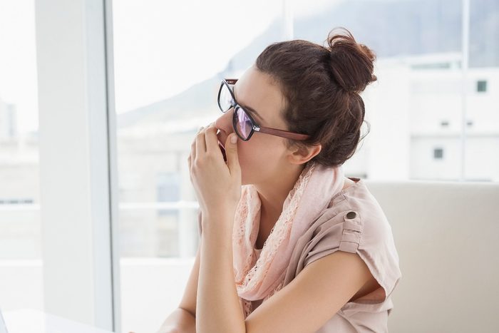 Woman with glasses yawning into her hand
