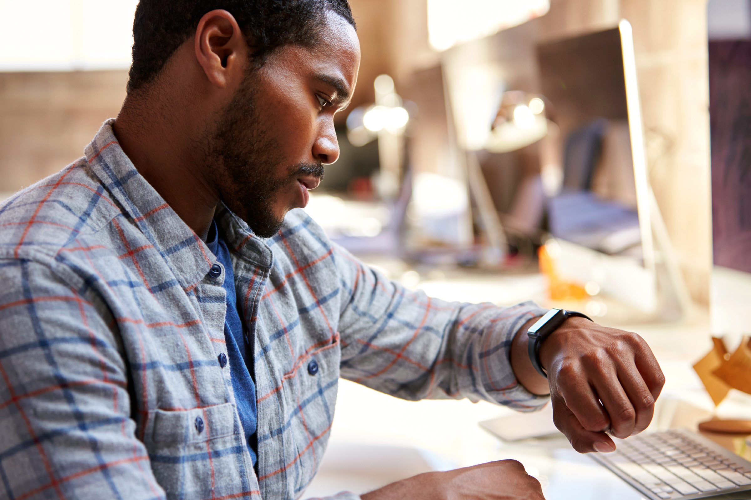 Black man checking his watch at his desk job