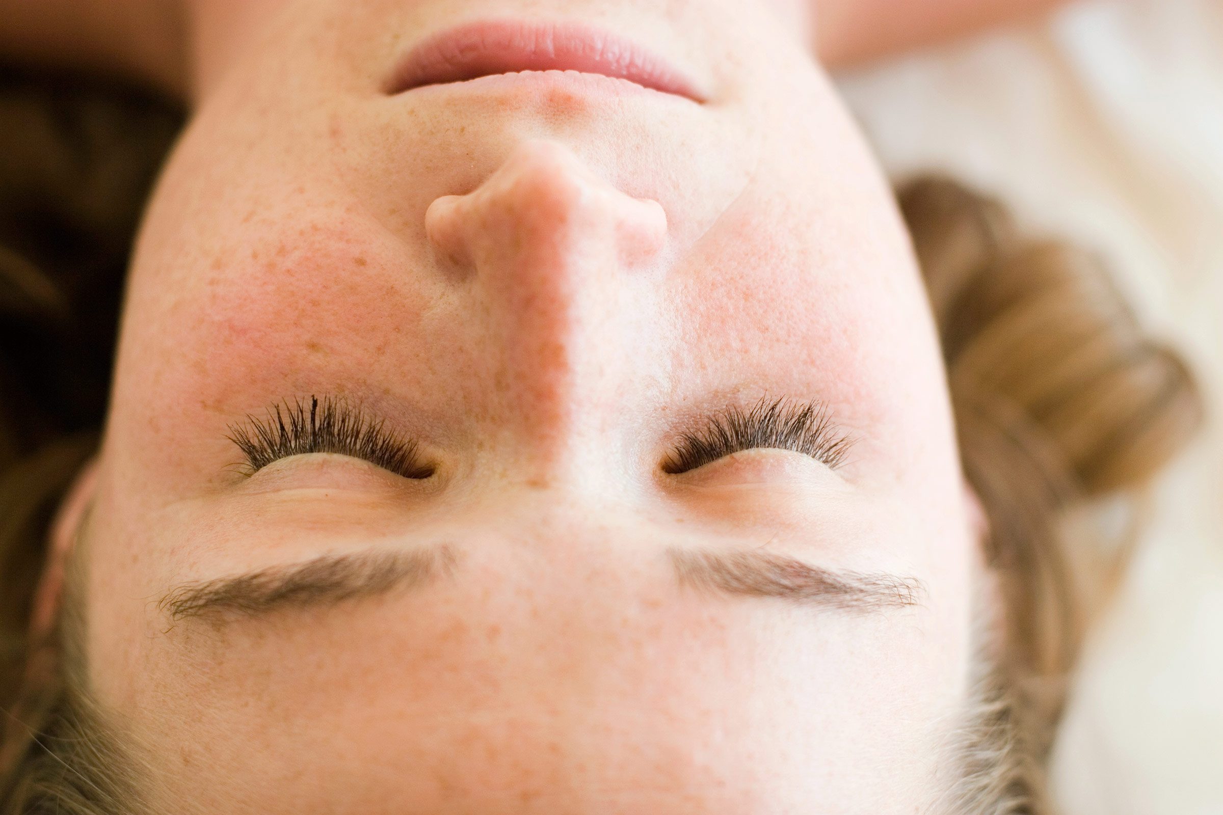 freckled woman with eyes closed lying on her back