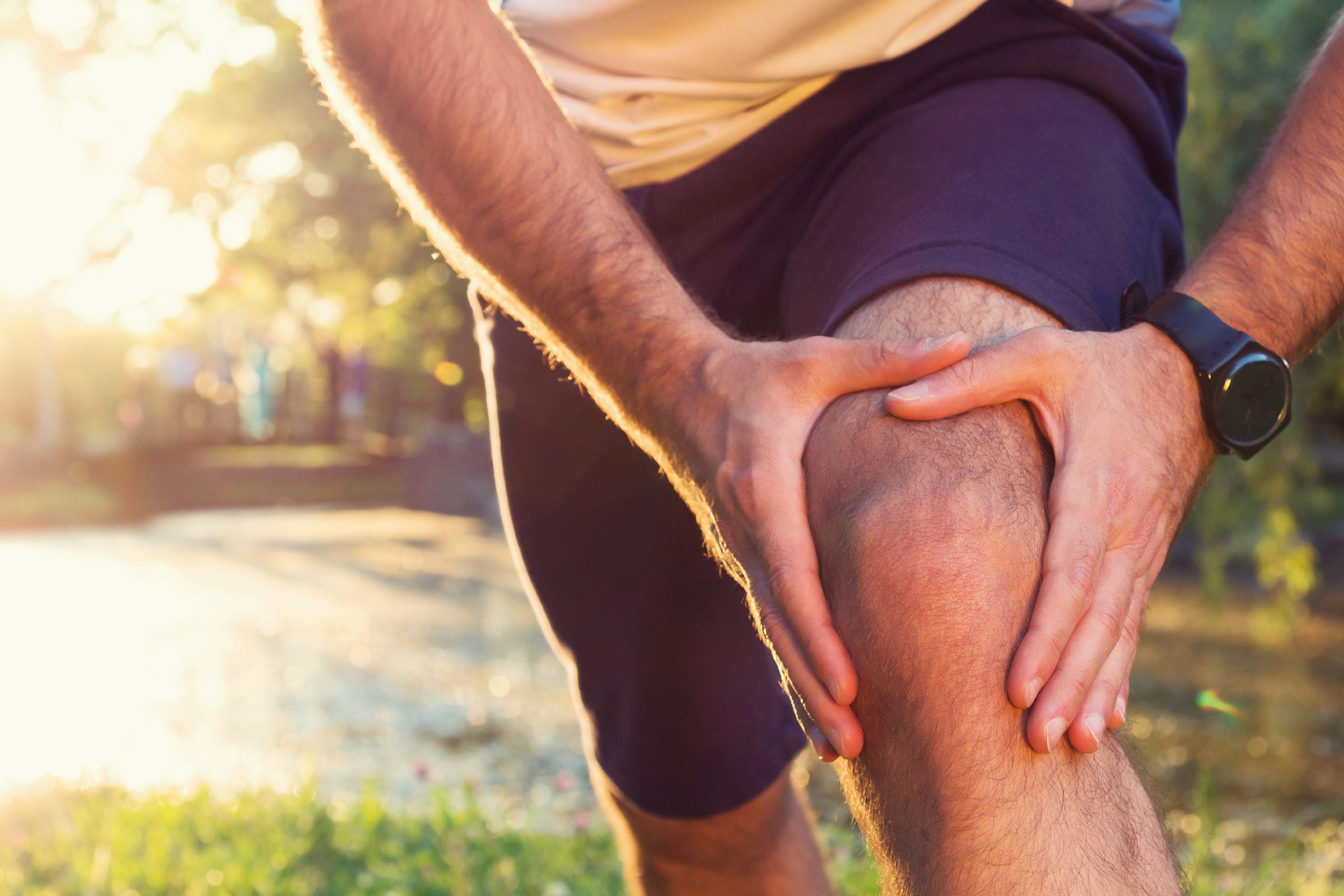 man outdoors holding his knee