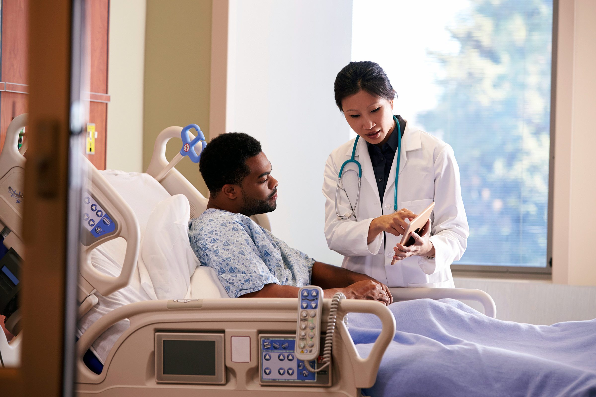 Asian doctor at the bedside of an African American patient