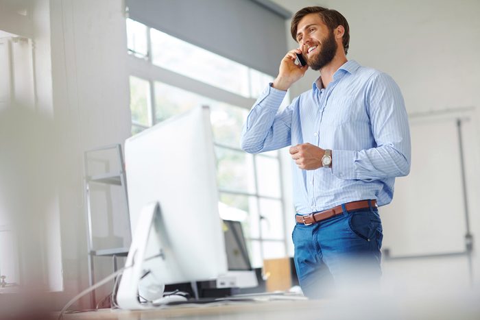 man standing at his desk talking on the phone