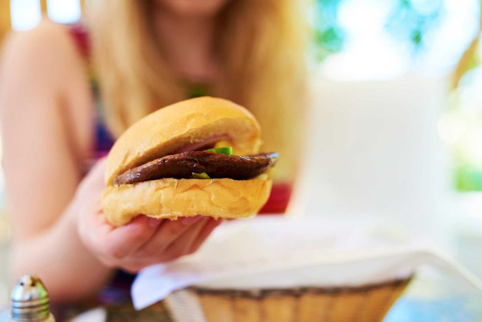 woman holding a hamburger in one hand