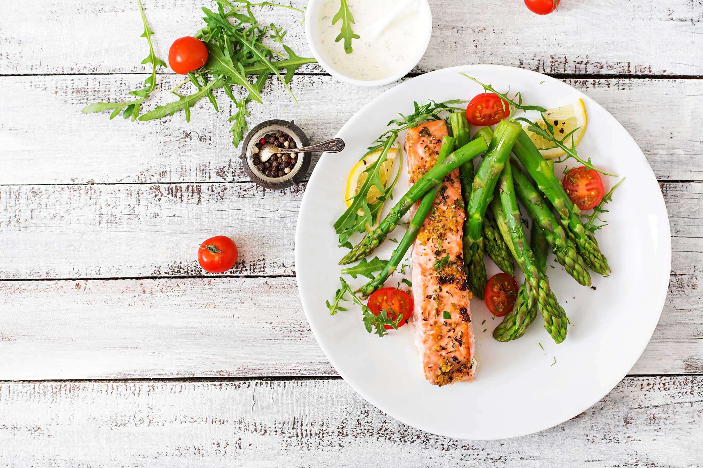 white plate with asparagus, salmon, dill, and lemon slices