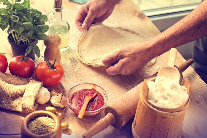 person prepping pizza dough