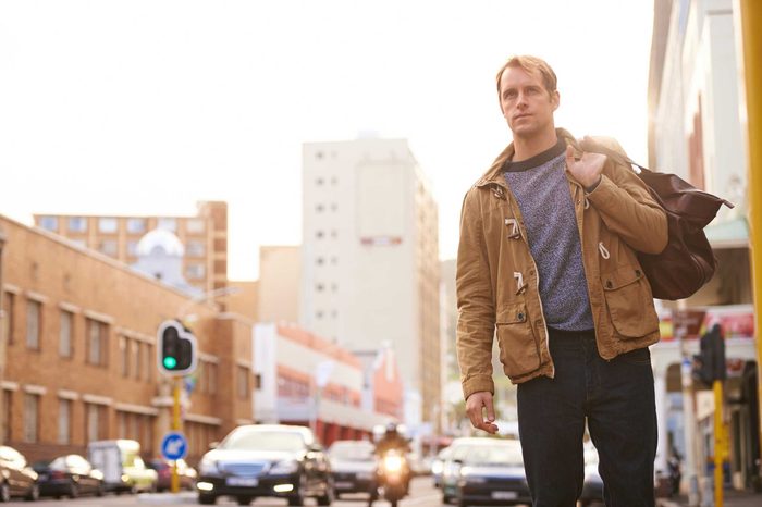 Man walking down a street wearing a jacket.