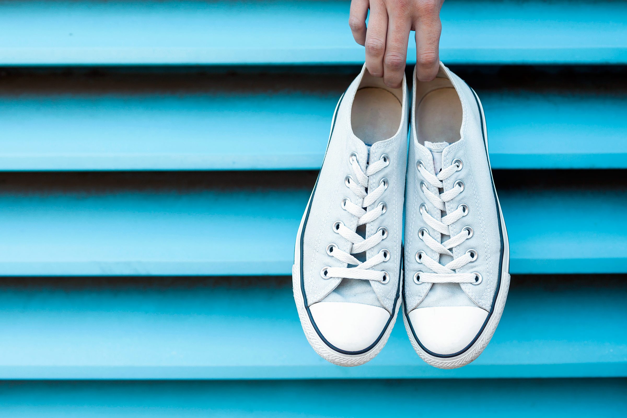 a hand holding a pair of sneakers