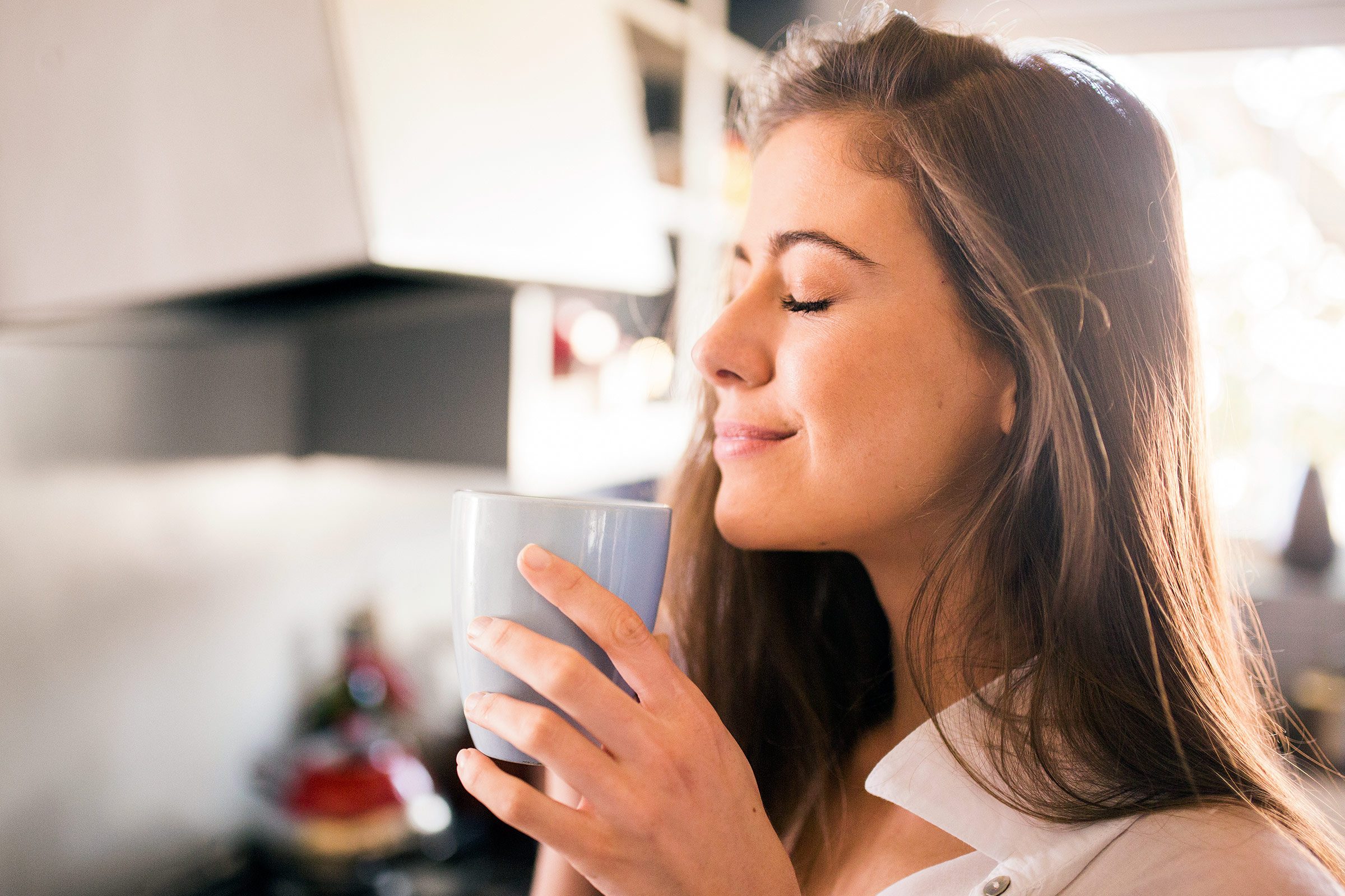 woman smiling and holding a cup of coffee