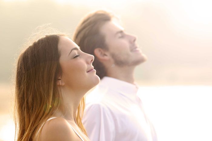 A couple looking happy and meditating in the sunlight.