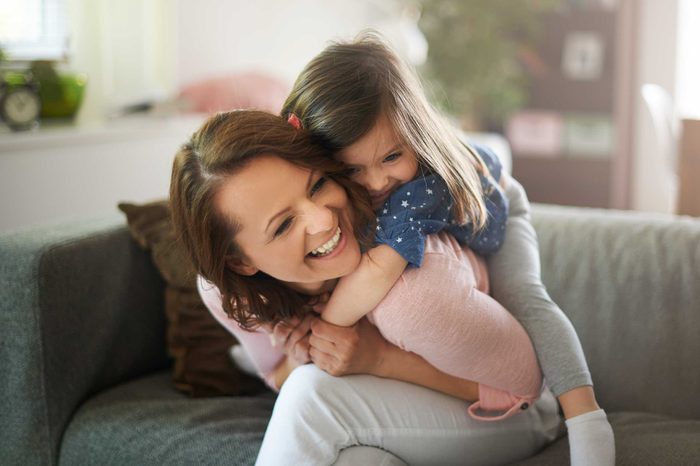 A little girl jumping on her mother's back.