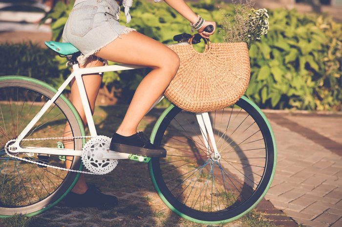 Woman with a purse pedaling on her bike outdoors.